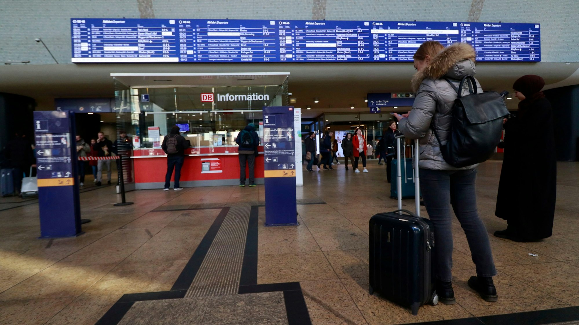 Im Foyer des HBF schauen sich Pendler die Abfahrtstafel an.