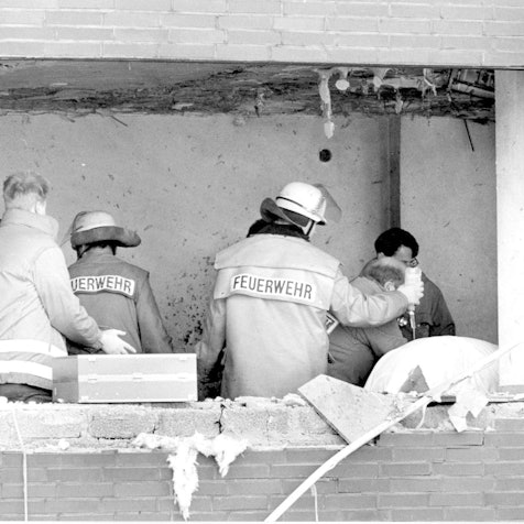 Das Bild zeigt Einsatzkräfte, de sich kurz nach dem Amoklauf um einen Verletzten im Gerichtssaal kümmern. In der Fassade klafft ein großes Loch.