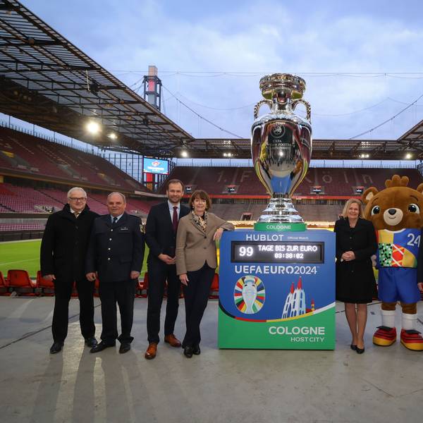 Henriette Reker und Nancy Faeser stehen mit xy neben einem großen Europapokal im Rhein-Energie-Stadion