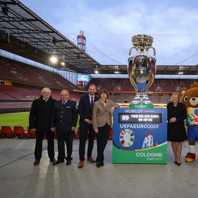 Henriette Reker und Nancy Faeser stehen mit xy neben einem großen Europapokal im Rhein-Energie-Stadion