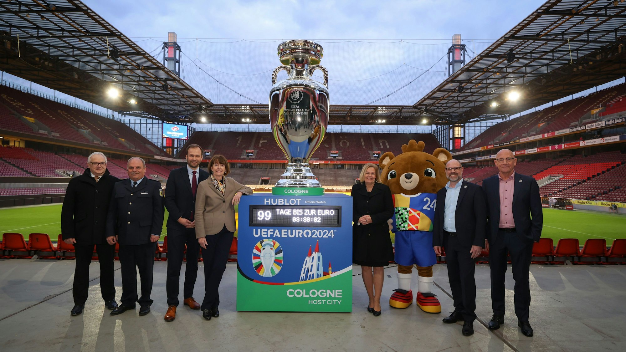 Henriette Reker und Nancy Faeser stehen mit xy neben einem großen Europapokal im Rhein-Energie-Stadion