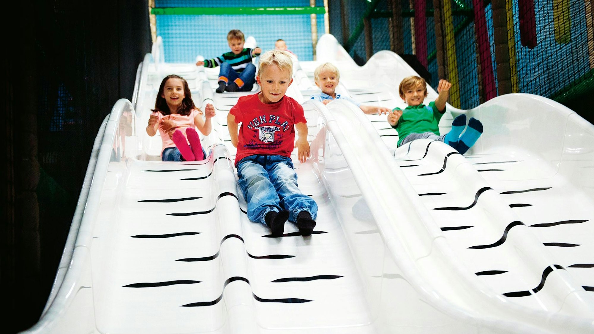 Zu sehen sind lachende Kinder auf einer riesigen Rutsche.