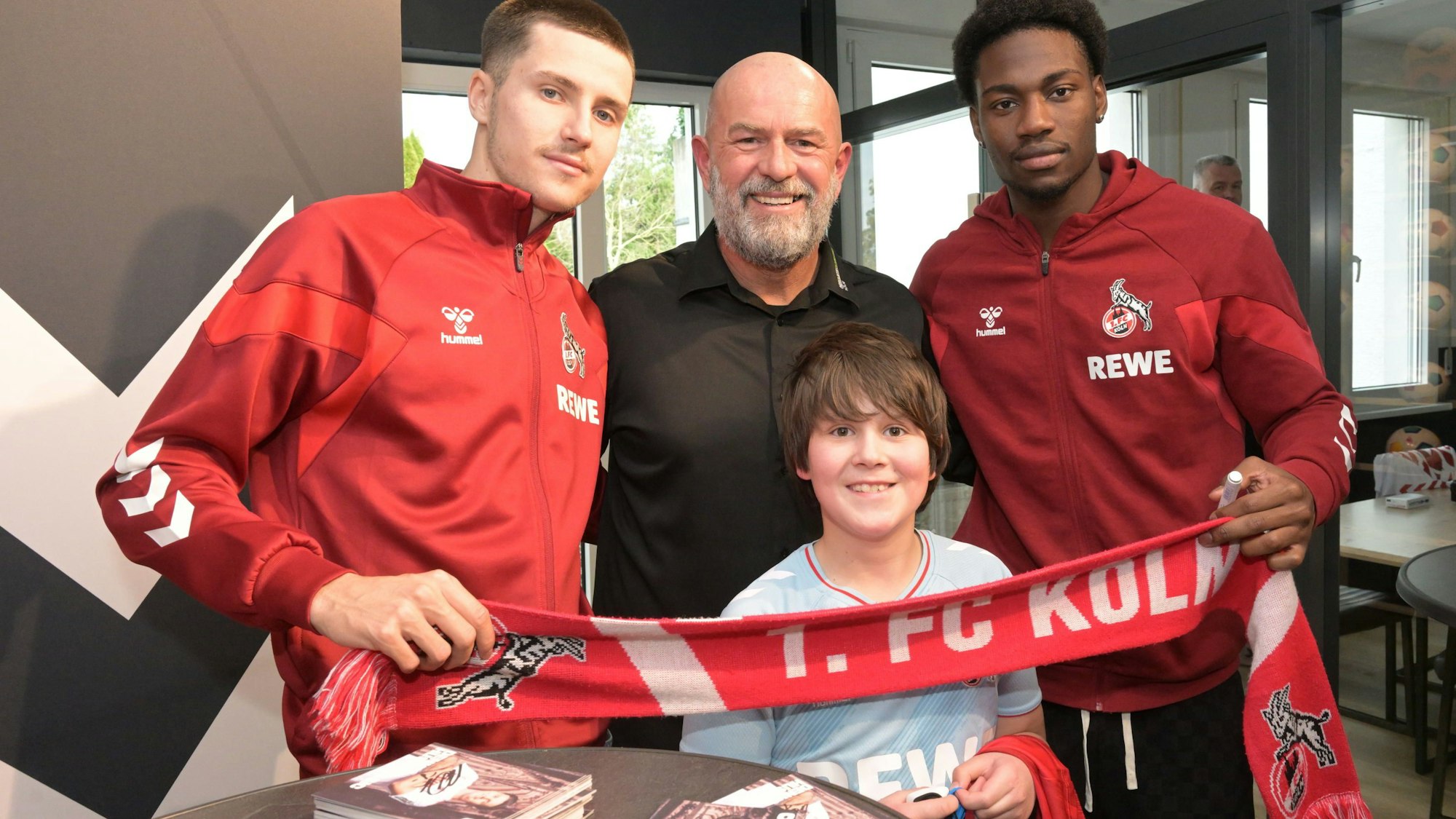 Die FC-Spieler Faride Alidou und Denis Huseinbasic mit Store-Manager Michael Brancato und Fan Vito bei Teamsport Refrath.