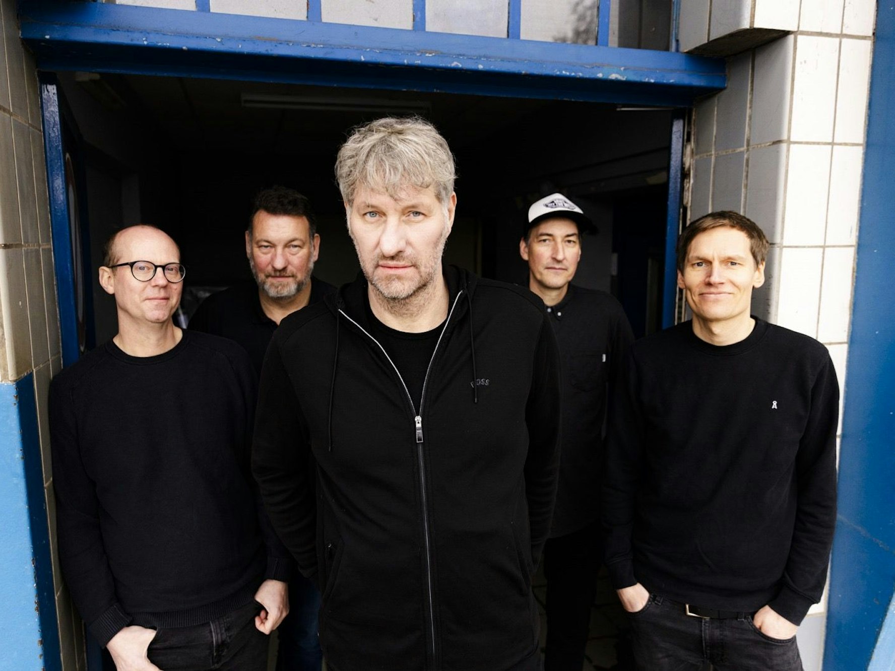 Die Band schaut, schwarz gekleidet, in die Kamera.