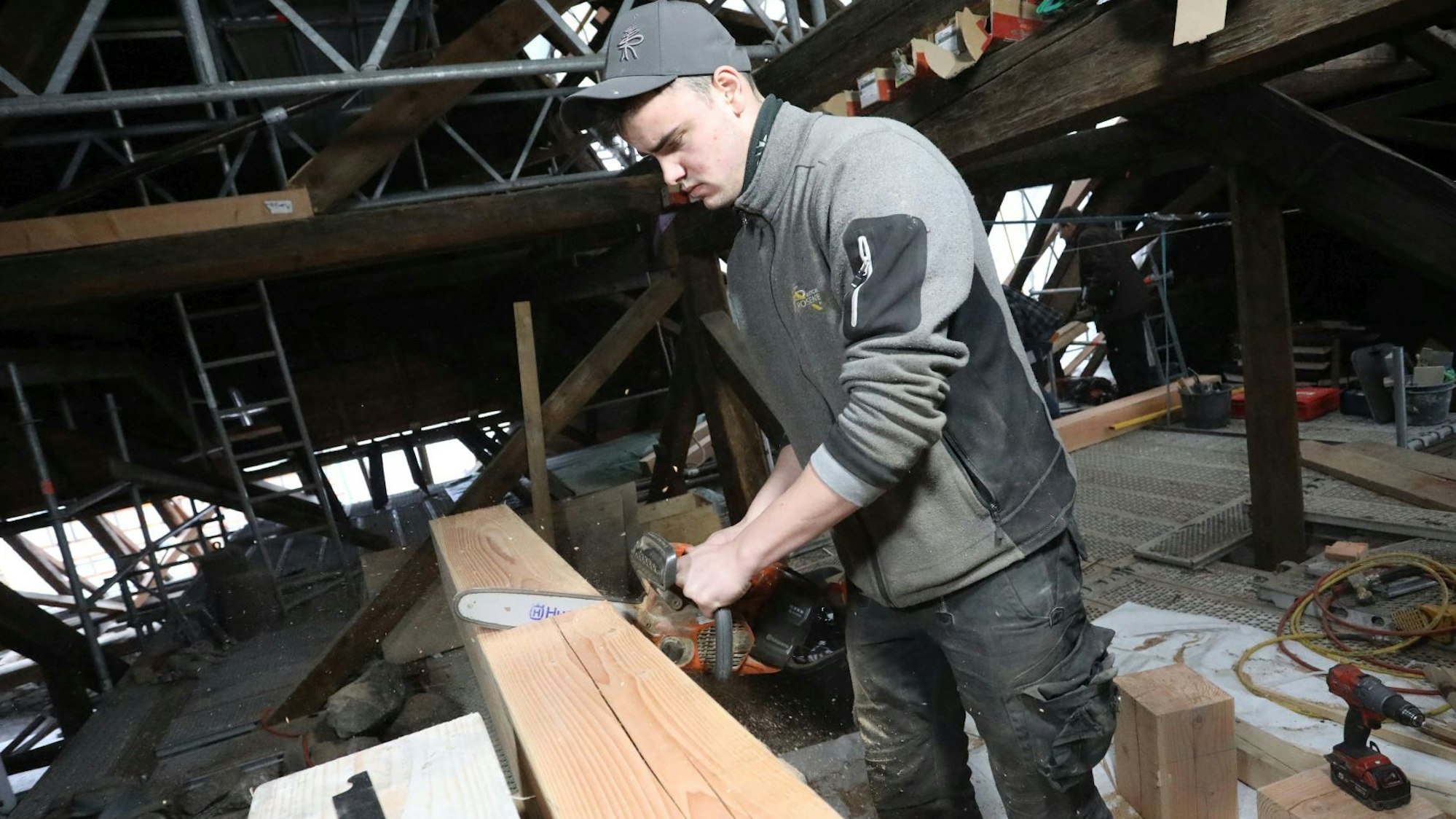 Ein Zimmermann sägt einen Balken durch.