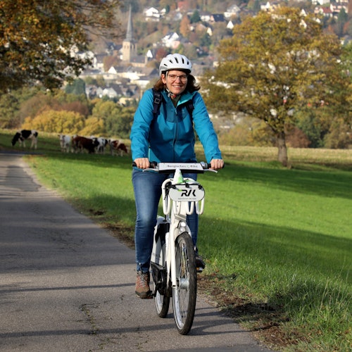 Eine E-Bike-Fahrerin auf einer Landstraße.