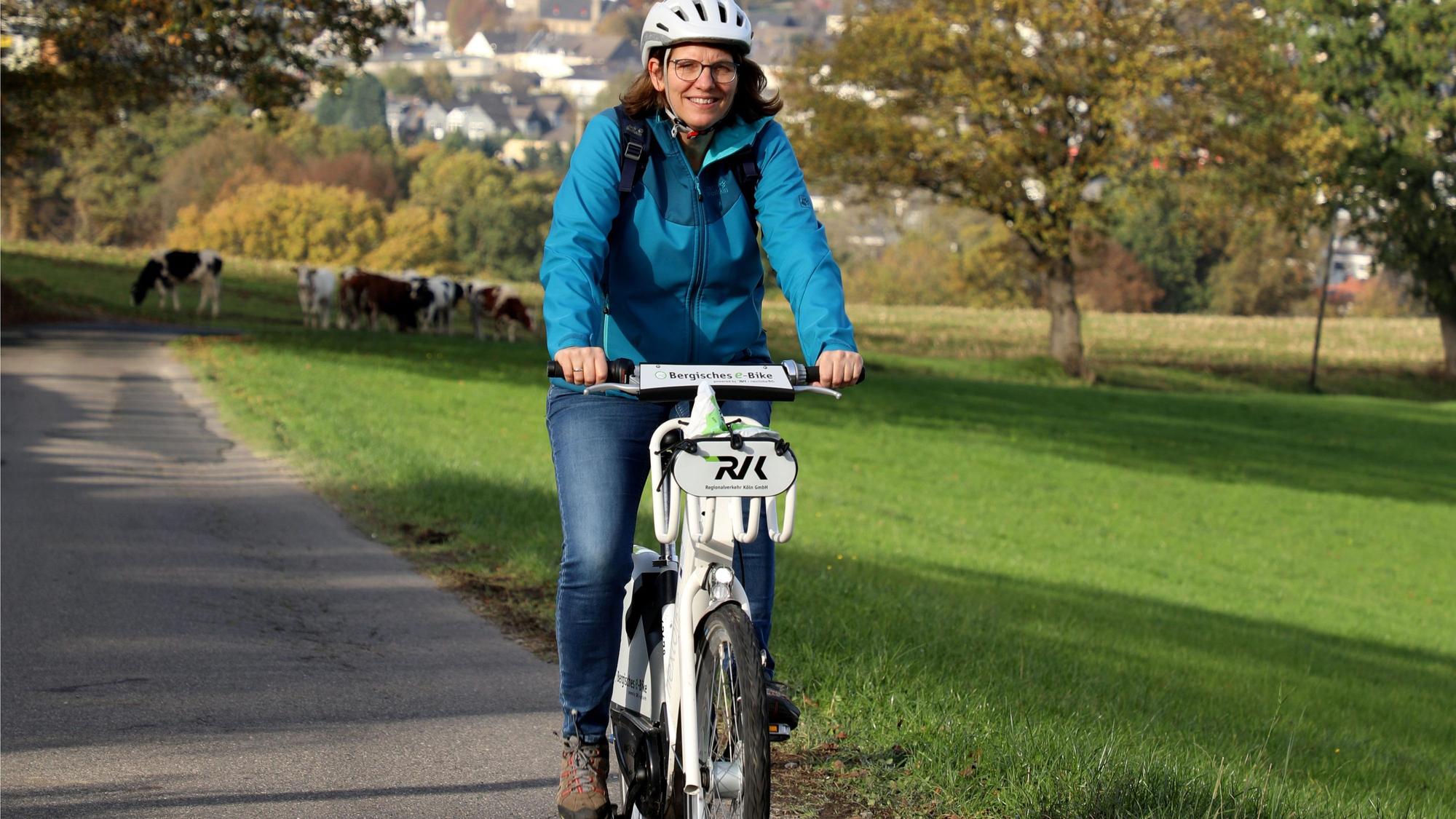 Eine E-Bike-Fahrerin auf einer Landstraße.