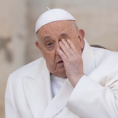 Papst Franziskus reibt sich mit der Hand das linke Auge.
