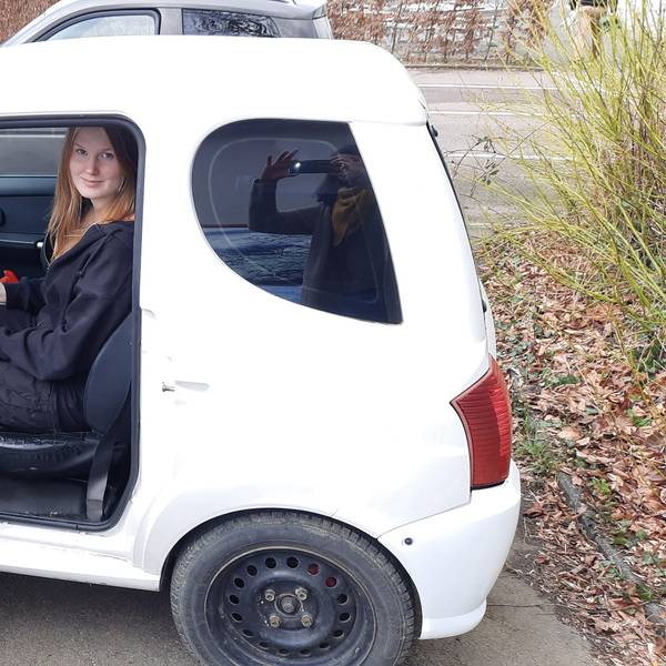 Eine Jugendliche sitzt auf dem Fahrersitz eines Micro-Cars, das Mini-Auto ist eine Alternative zum Mofa.