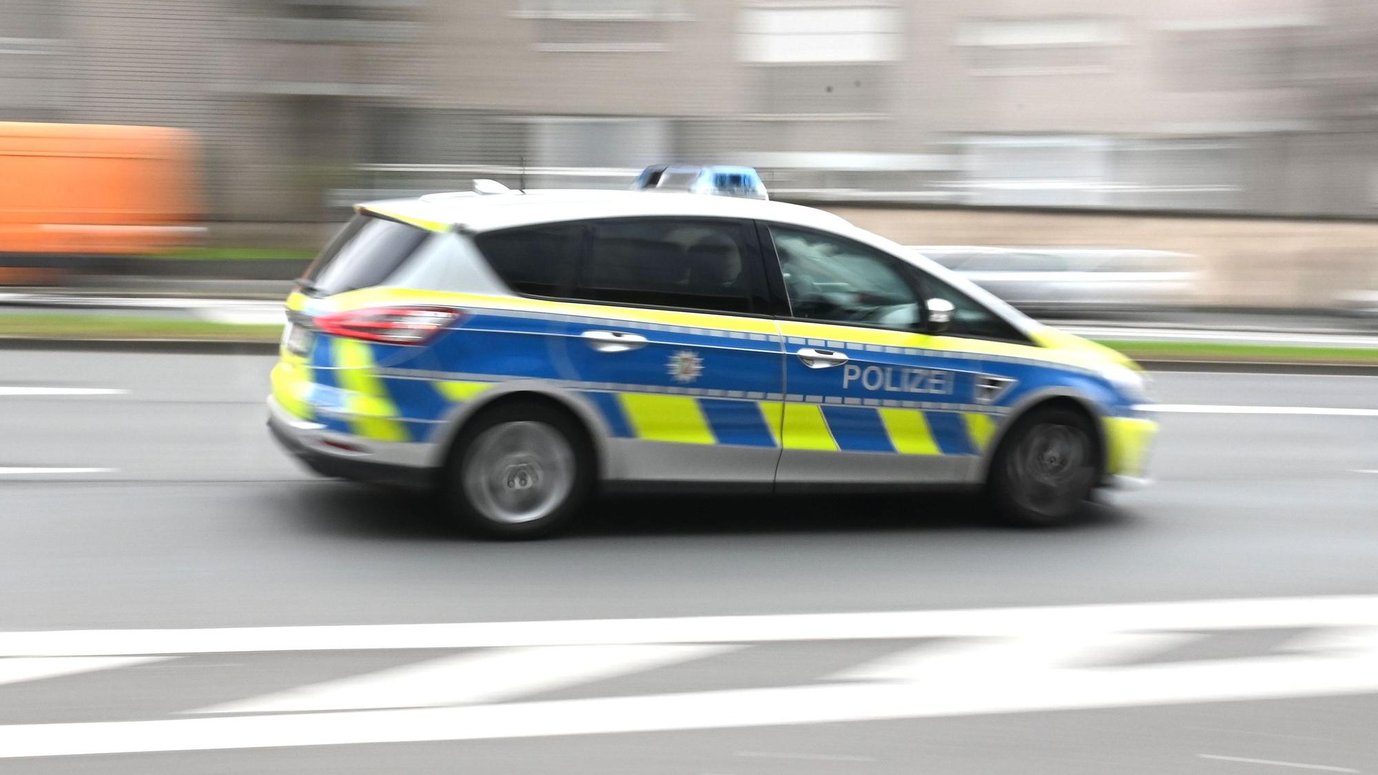 Zu sehen ist ein Einsatzfahrzeug der Kölner Polizei in der Seitenansicht, das durch die Innenstadt rast.