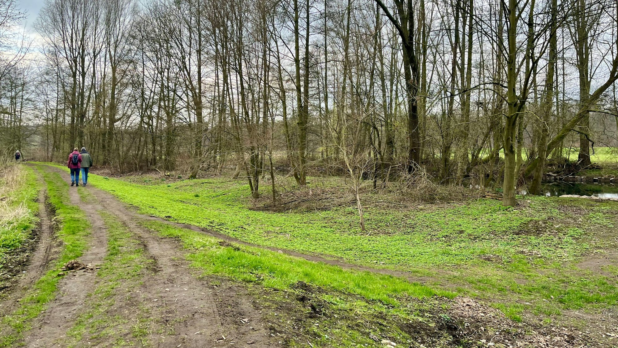 Menschen gehen an einem Fluss spazieren.