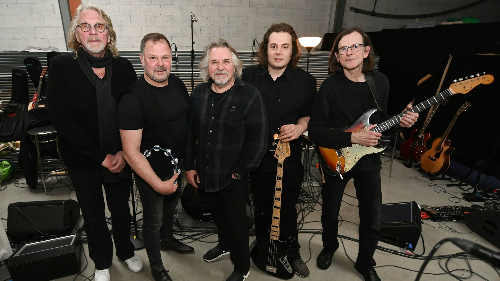 Jürgen Fritz, Ilja Engel, Tommy Engel, Robin Duns und Markus Wienströer stehen mit Instrumenten nebeneinander in ihrem Probenraum.