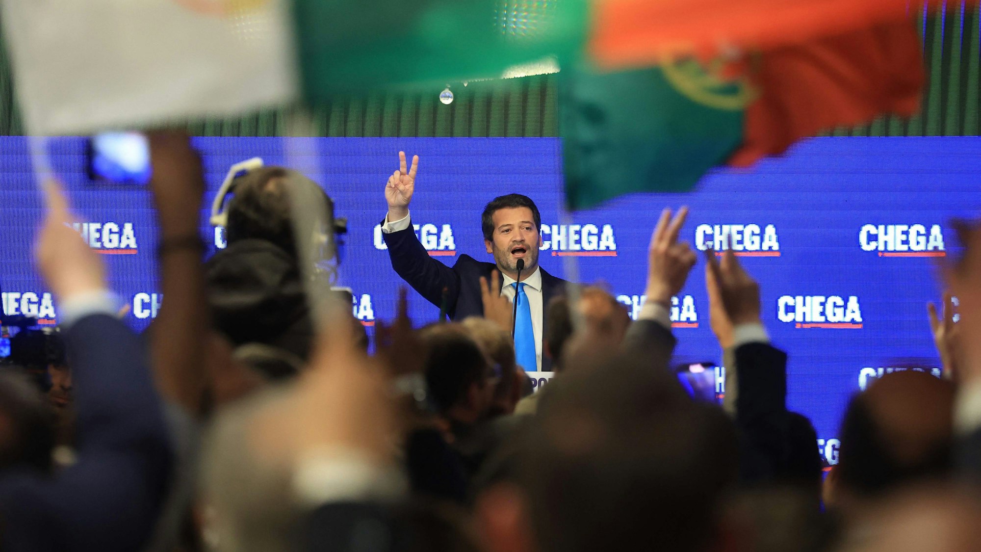 André Ventura, Chega-Vorsitzender, formt zwei Finger zu einem Siegeszeichen auf der Bühne vor Anhängern seiner Partei.