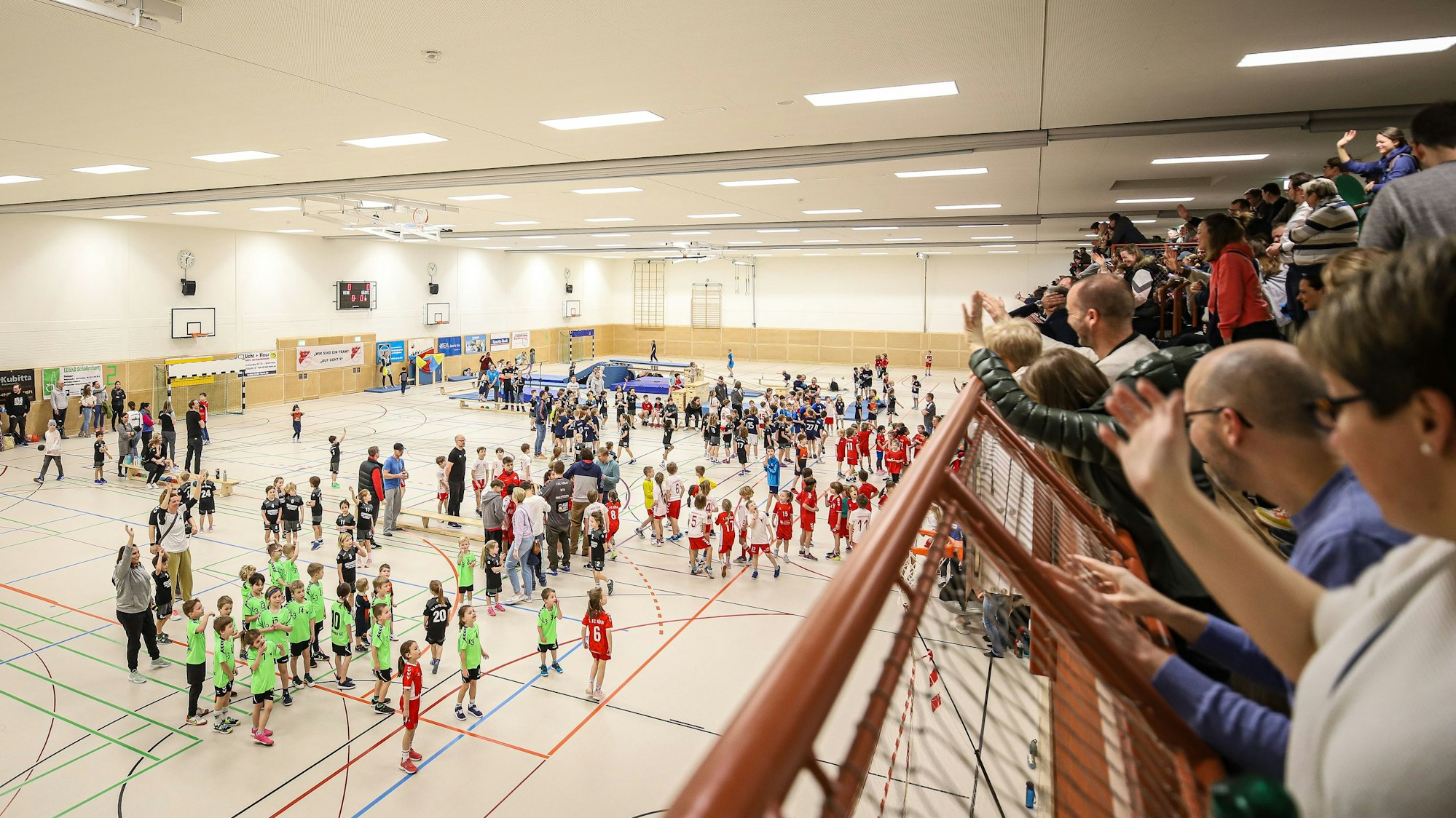 Kinder auf dem Spielfeld, Erwachsene auf der Tribüne