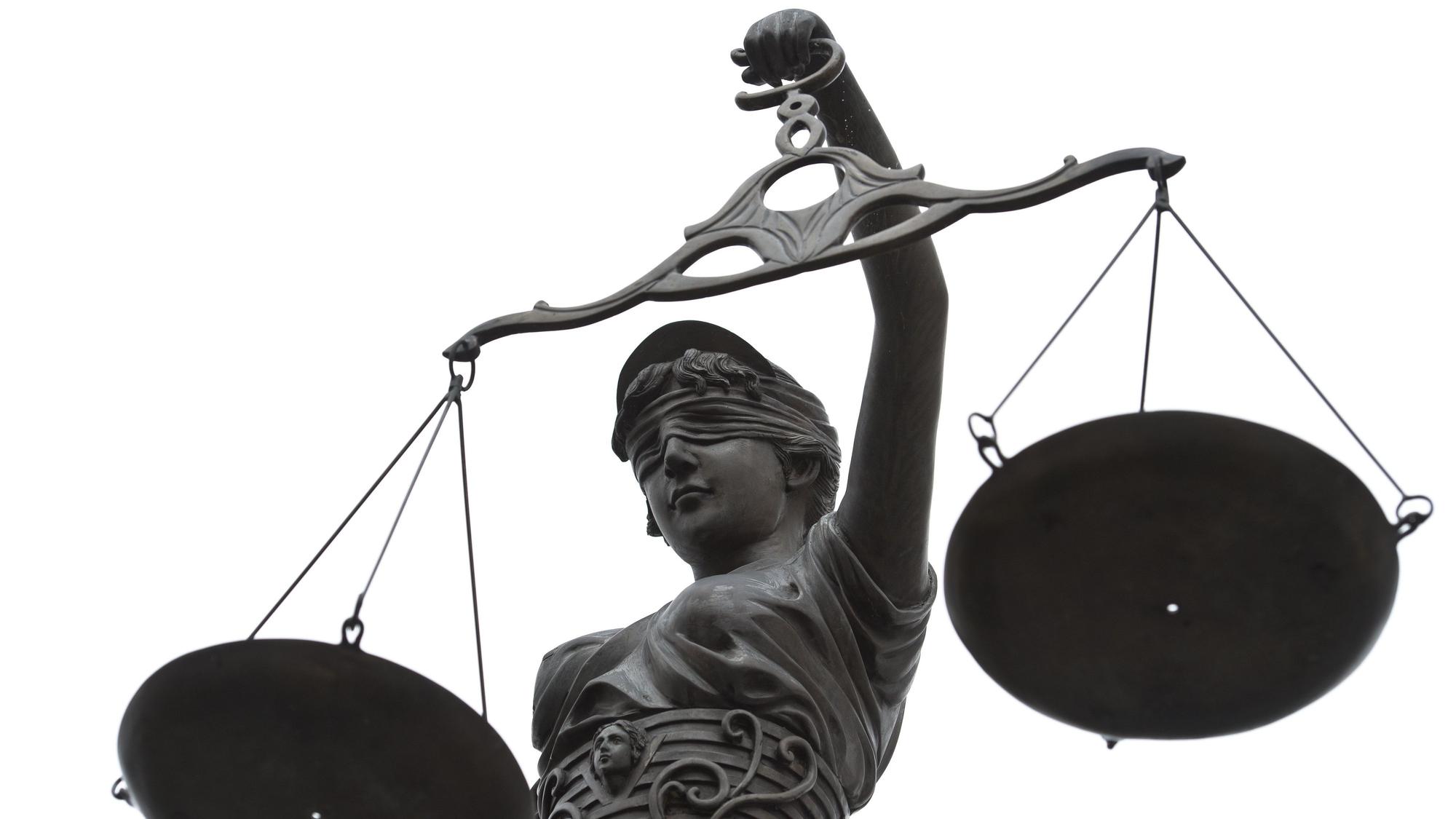 Eine Statue der Justitia mit einer Waage in ihrer Hand.