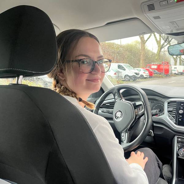 Mia Walther sitzt in einem Auto und guckt schräg über ihre Schulter in die Kamera.