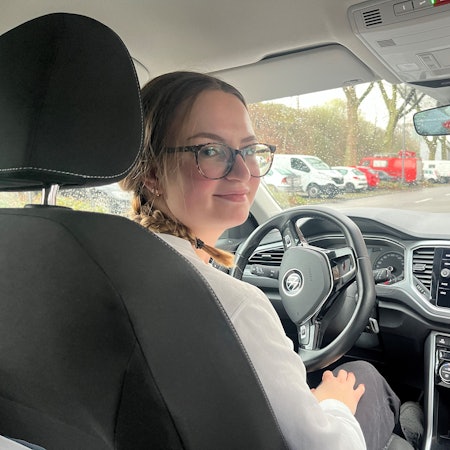 Mia Walther sitzt in einem Auto und guckt schräg über ihre Schulter in die Kamera.