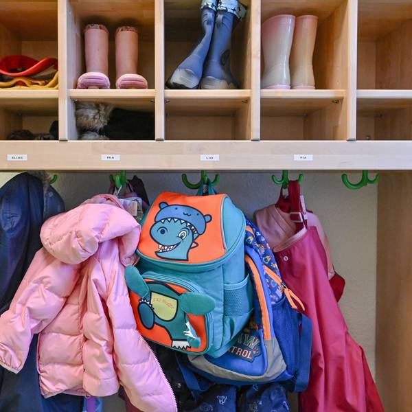 Kleidung von Kindern hängt in einem Kindergarten.