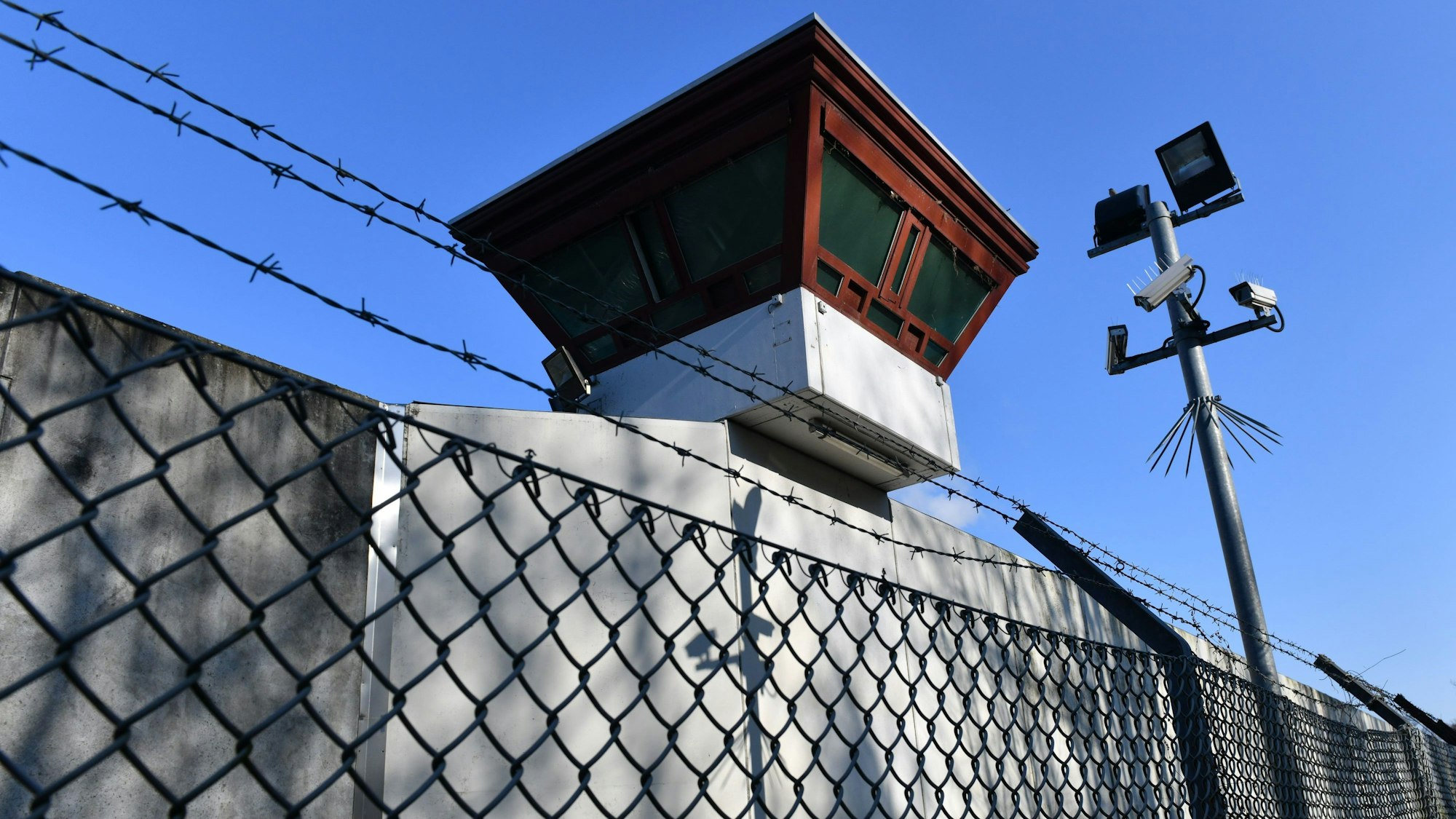 Sicherheitsleuchten und Überwachungskameras sind vor einem Gebäude auf dem Gelände der Justizvollzugsanstalt