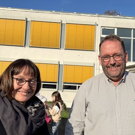 Ein Mann steht vor einem großen Schild, auf dem Schule IM Süden steht.