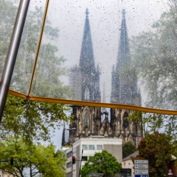 Regenwetter in Köln, Blick auf den Kölner Dom durch einen durchsichtigen Regenschirm.