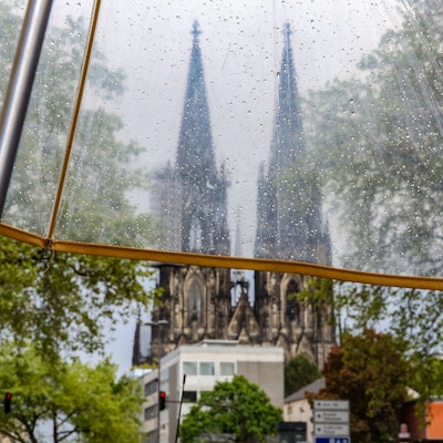 Regenwetter in Köln, Blick auf den Kölner Dom durch einen durchsichtigen Regenschirm.