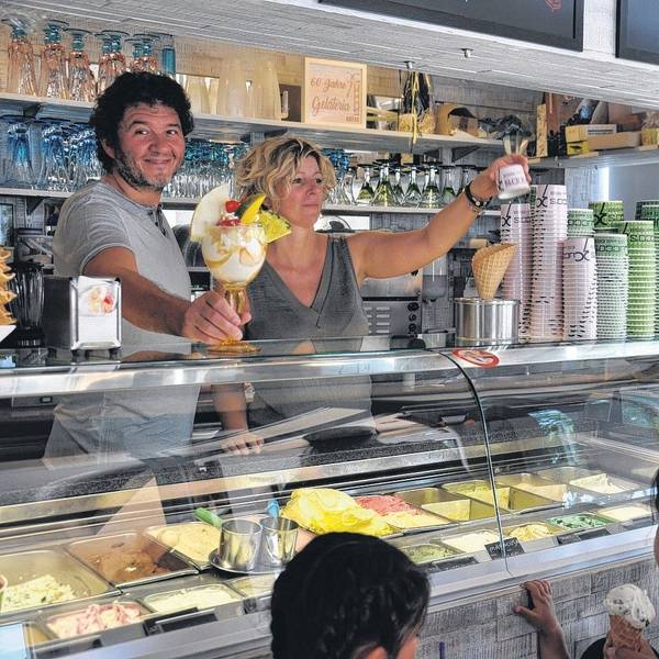 Seit Jahrzehnten versorgen Lorenzo Cucco und Nicoletta Bez Elsdorf mit Speiseeis. Hier stehen sie hinter der Eistheke, eine Frau mit Kindern wird bedient.