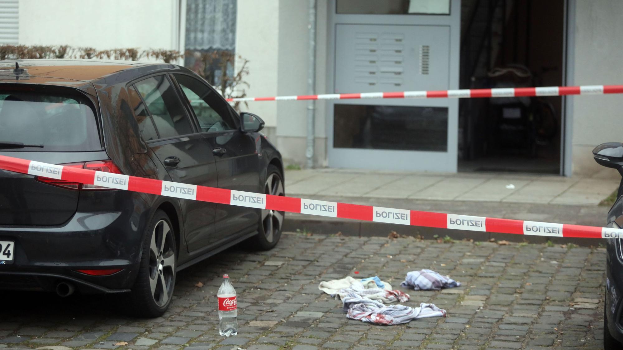 Ein Golf ist in einer Parktasche geparkt, daneben liegen blutige Handtücher, im Vordergrund ist Absperrband der Polizei zu sehen.