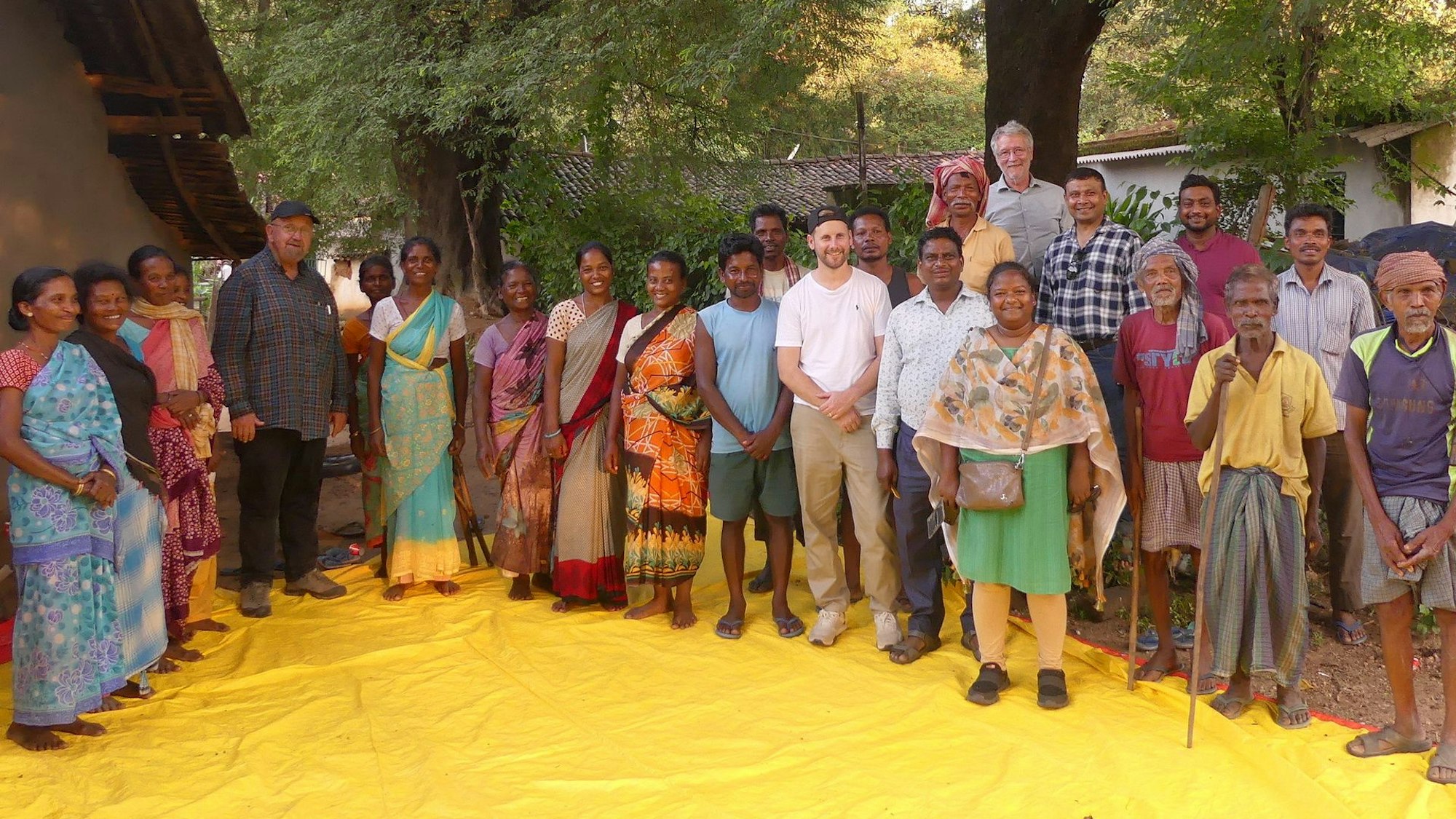 Eine Gruppe von Dorfbewohnern empfängt eine Besuchergruppe aus Deutschland. Die Frauen tragen traditionelle Saris.