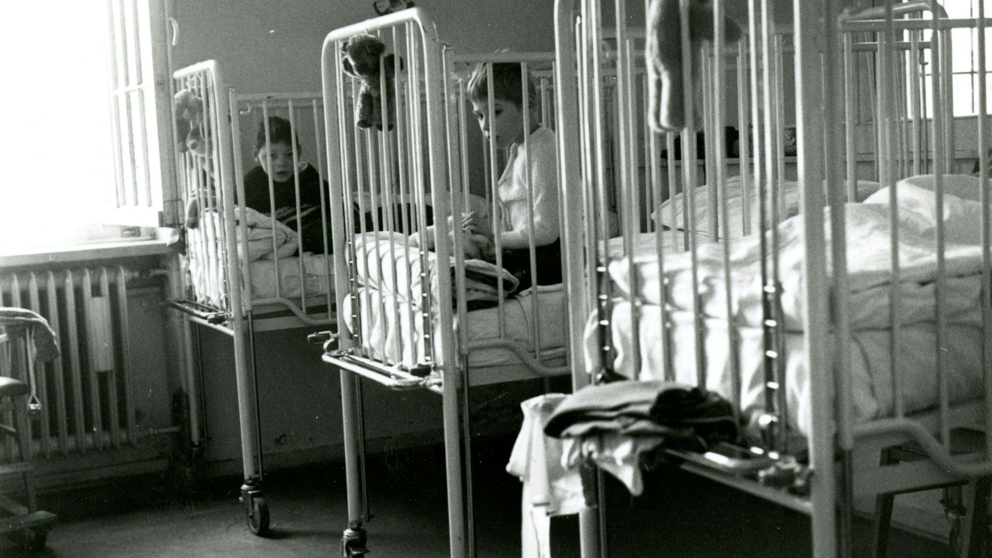 Heimkinder in Gitterbetten im Landeskrankenhaus Bonn des LVR. Das Aufnahmedatum der Schwarzweißfotografie liegt zwischen 1950 und 1970.