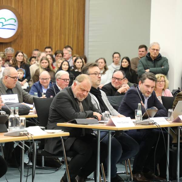 Die Politiker und Politikerinnen von Grünen und CDU sitzen im Kreistag im Kreishaus des Rheinisch-Bergischen Kreises an Tischen. Im Hintergrund sind Zuschauerinnen und Zuschauer zu sehen.