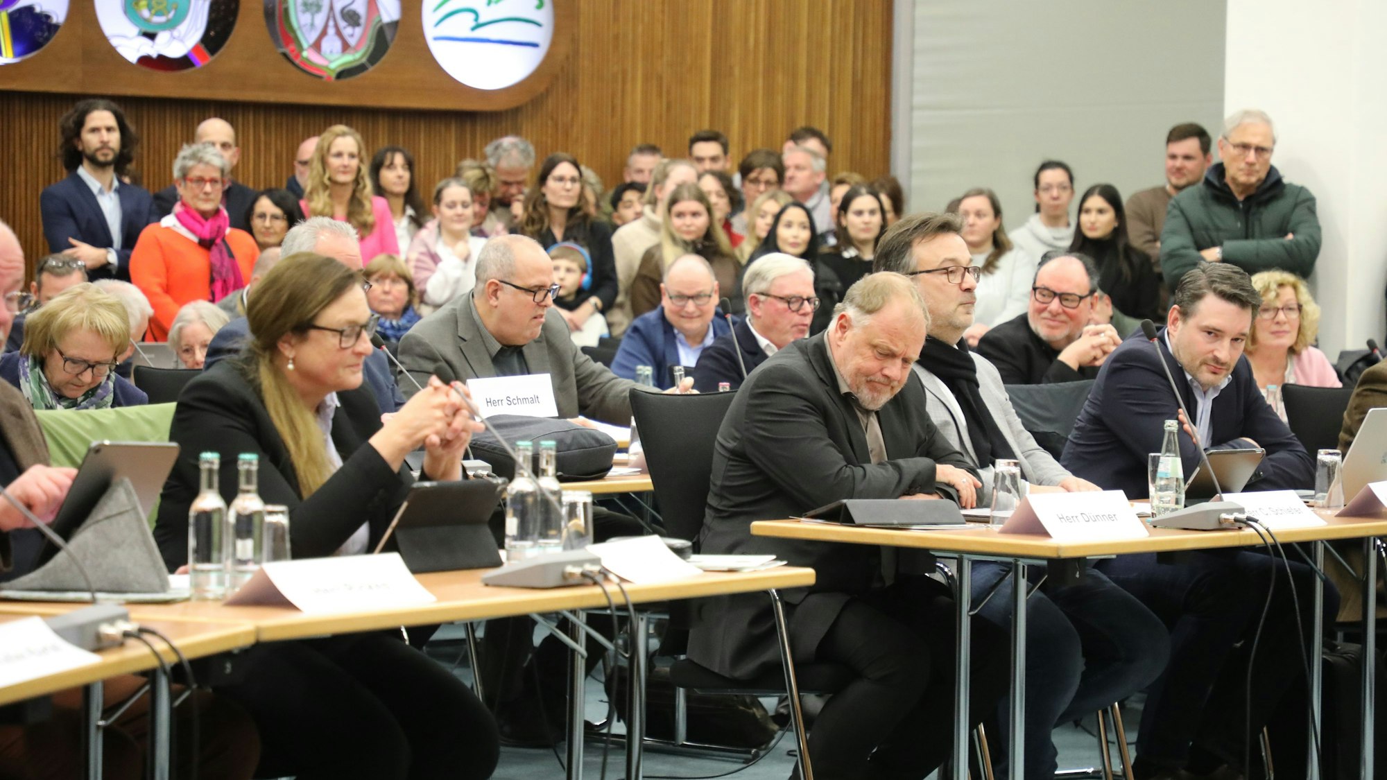 Die Politiker und Politikerinnen von Grünen und CDU sitzen im Kreistag im Kreishaus des Rheinisch-Bergischen Kreises an Tischen. Im Hintergrund sind Zuschauerinnen und Zuschauer zu sehen.