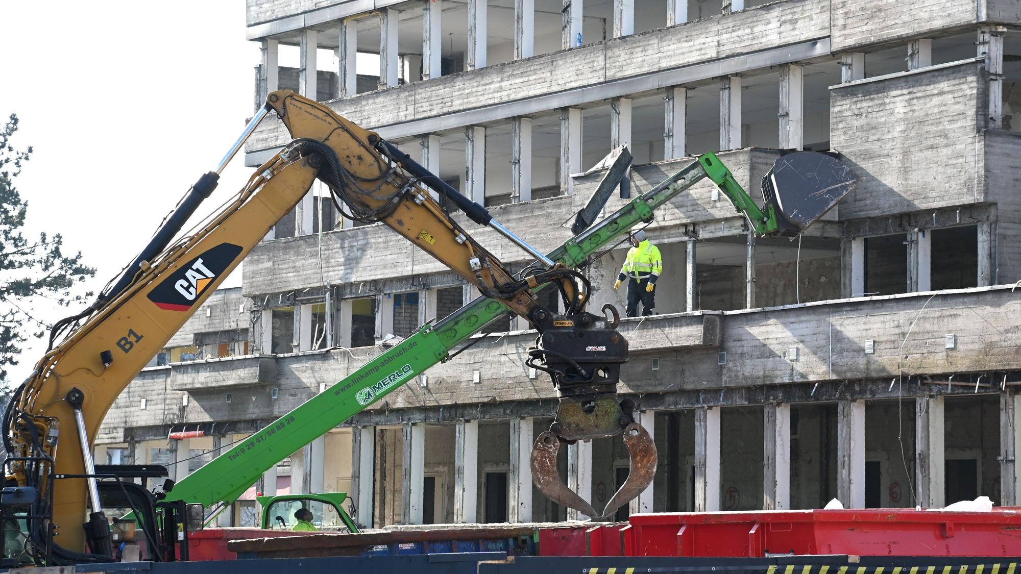 Blick auf einen mehrgeschossiges entkerntes Beton-Gebäude, an dem Bagger arbeiten.