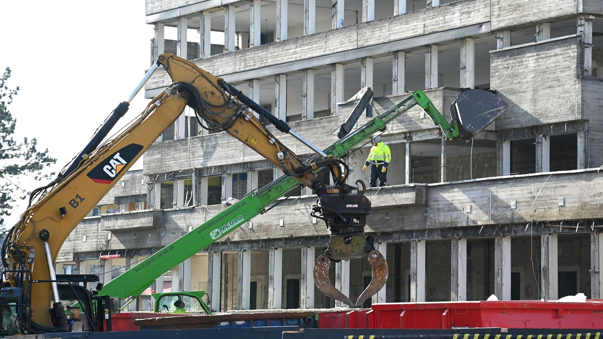 Blick auf einen mehrgeschossiges entkerntes Beton-Gebäude, an dem Bagger arbeiten.