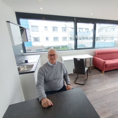 Ein Mann sitzt an einem Tisch in einem Appartement