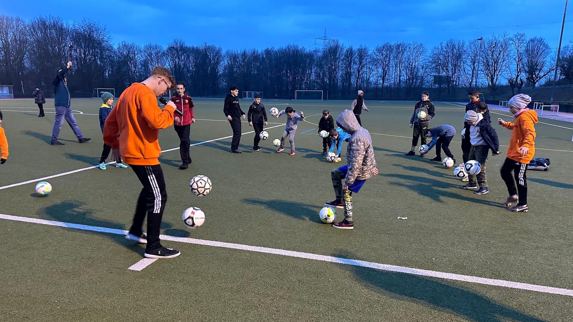 Jannik Singspiel, im Internet bekannt als Jannik Freestyle, zeigt jungen Fußballerinnen und Fußballern auf dem Sportplatz des FC Sankt Augustin Tricks.