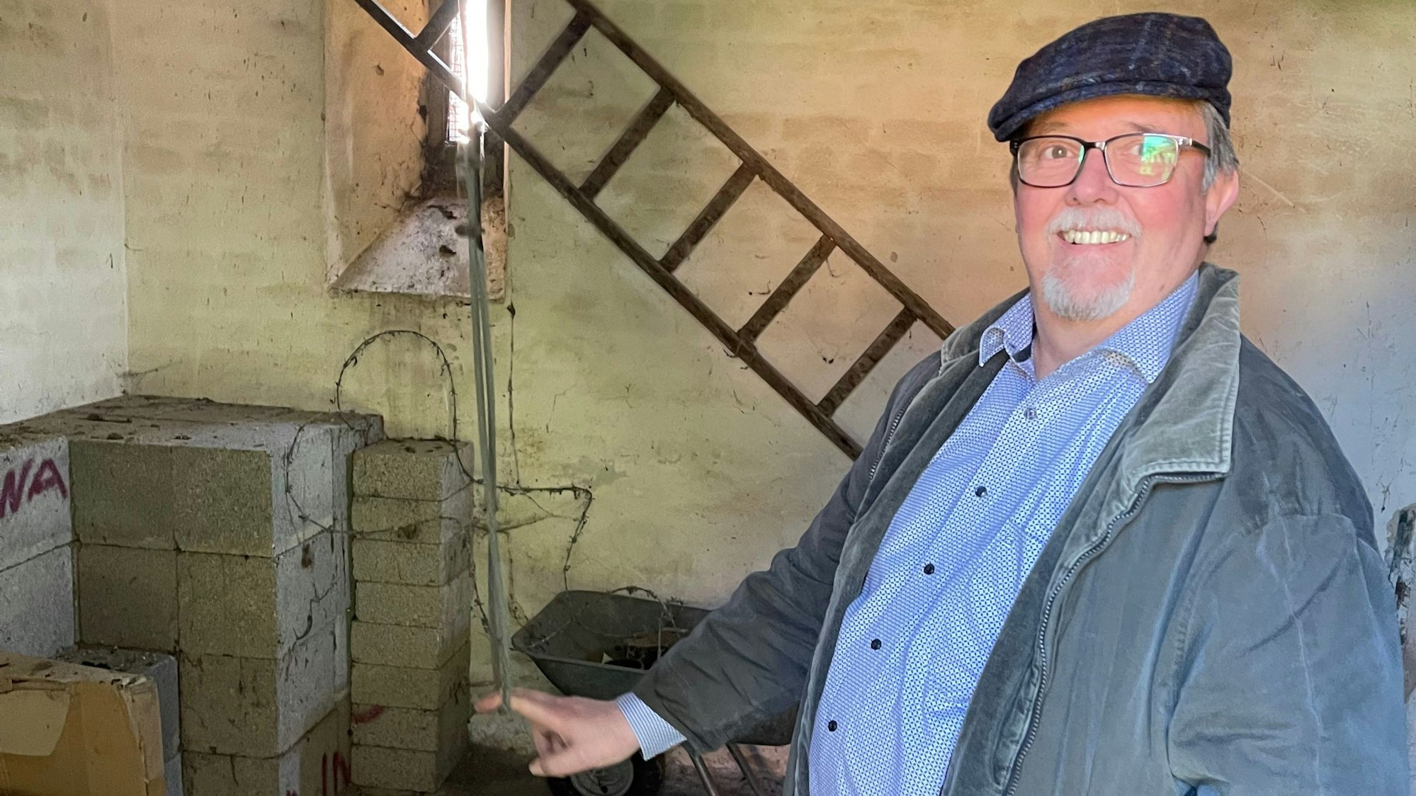 Ein Mann mit Schiebermütze und Brille zieht an einem dünnen Seil.