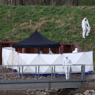 Spurensicherer der Polizei untersuchen eine Böschung am Tatort im Mülheimer Hafen.