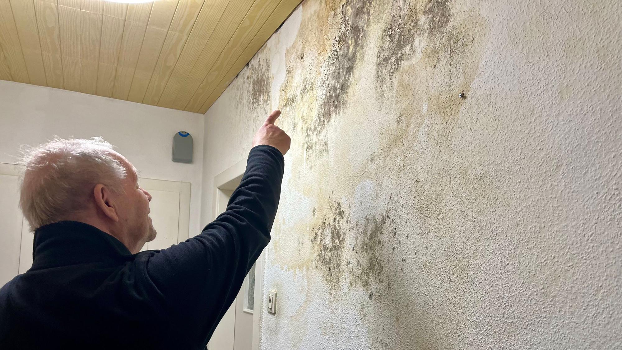 Mann zeigt auf großen Schimmelfleck an der Wand