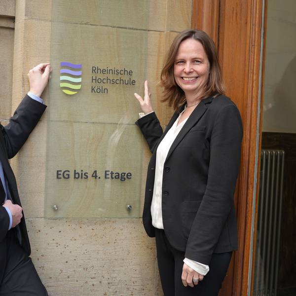 Martin Topp, Geschäftsführer und Kanzler, und Präsidentin Claudia Bornemeyer zeigen auf das neue Logo der umbenannten Rheinischen Hochschule