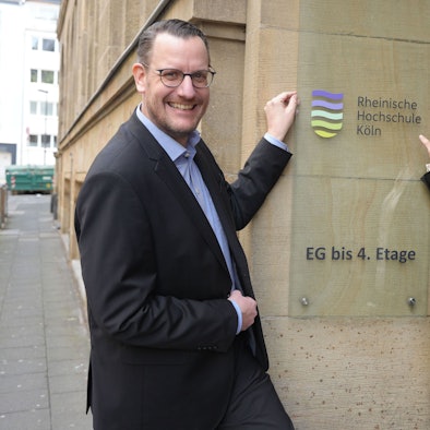 Martin Topp, Geschäftsführer und Kanzler, und Präsidentin Claudia Bornemeyer zeigen auf das neue Logo der umbenannten Rheinischen Hochschule