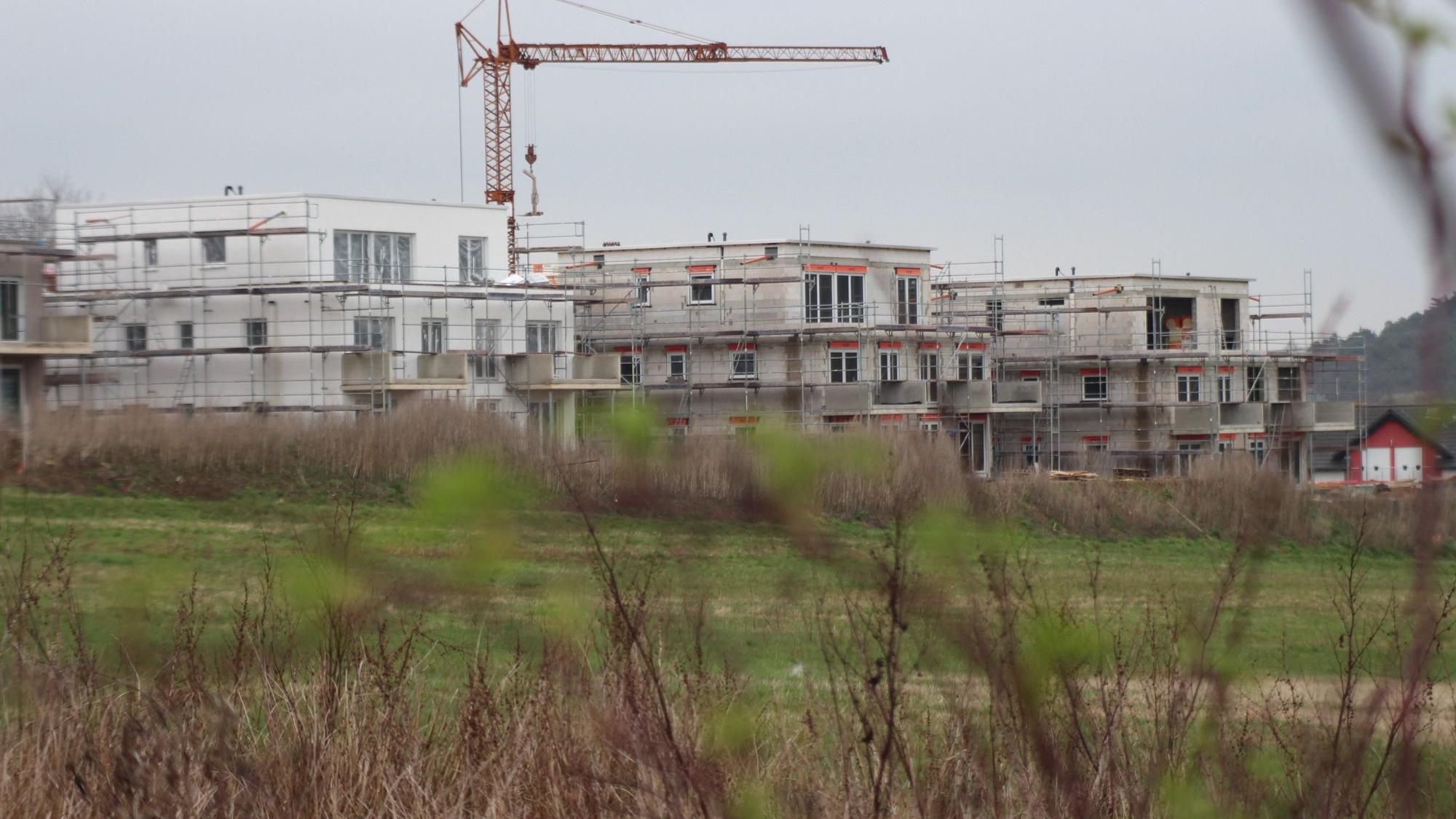 Das Bild zeigt drei im Bau befindliche Mehrfamilienhäuser.