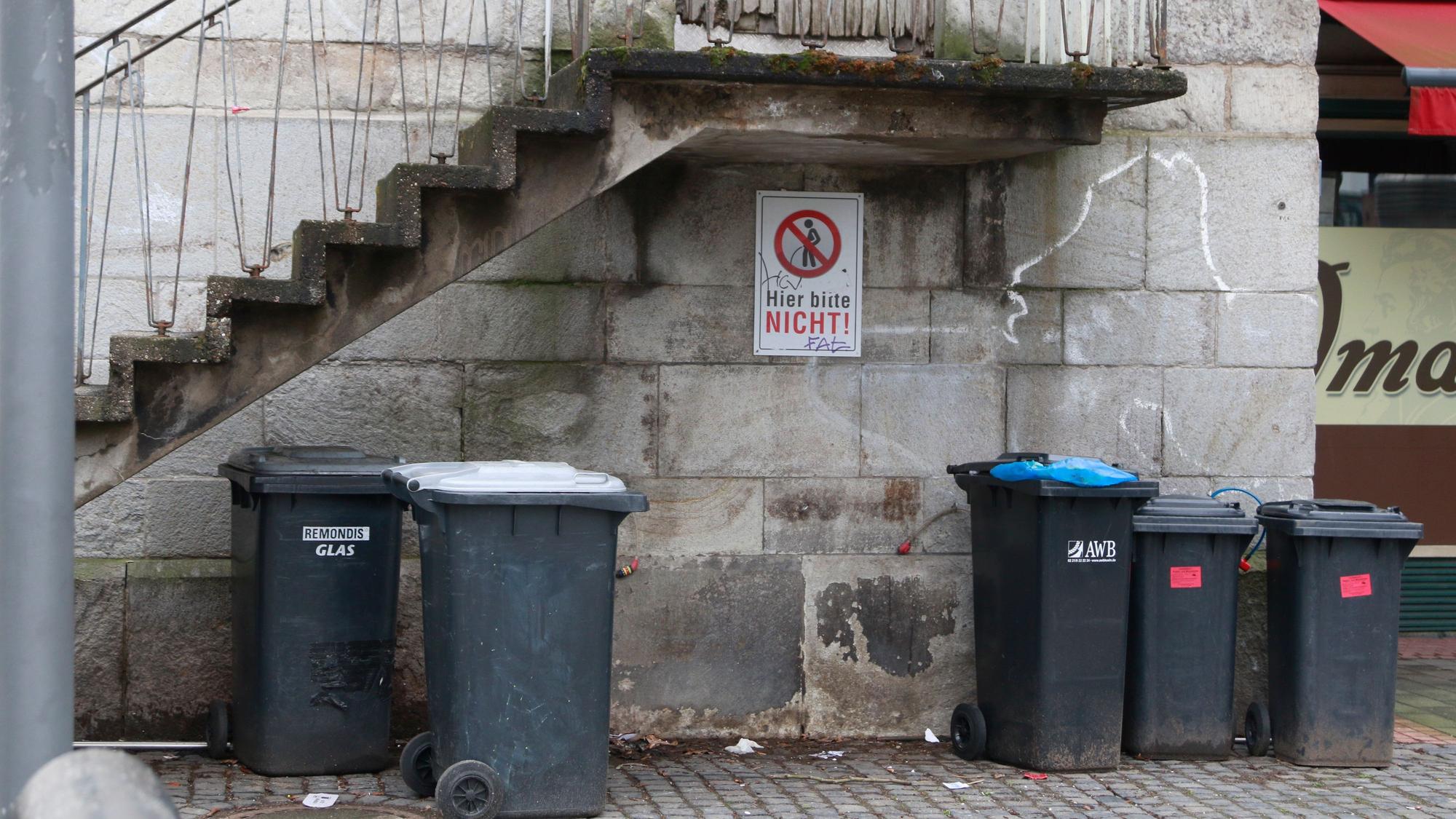 Unter der Treppe vom Eingang von der ehemaligen Pfarrkirche Klein St. Martin ist ein Hinweisschild angebracht "Bitte Nicht" und zeigt eine durchgestrichene Figur die ihre Notdurft verrichtet.