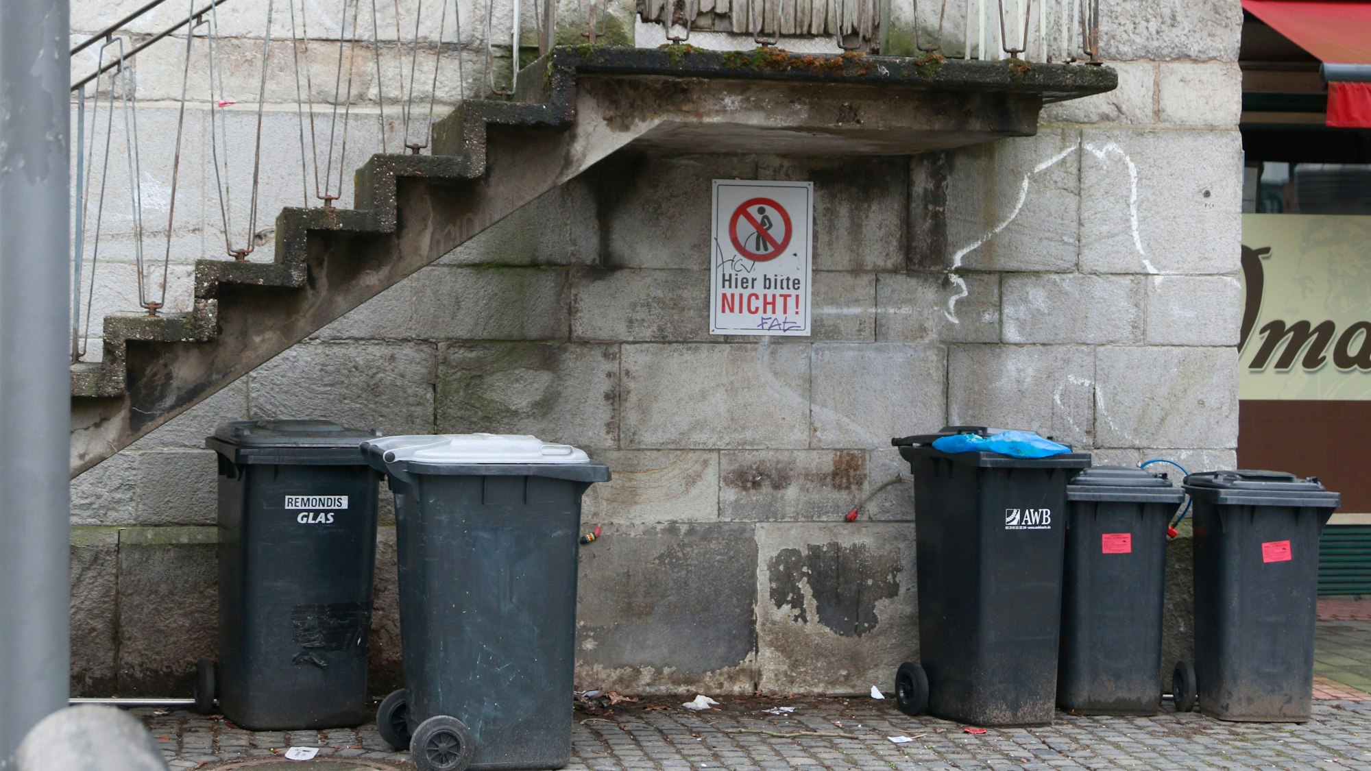 Unter der Treppe vom Eingang von der ehemaligen Pfarrkirche Klein St. Martin ist ein Hinweisschild angebracht "Bitte Nicht" und zeigt eine durchgestrichene Figur die ihre Notdurft verrichtet.