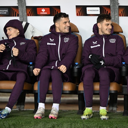 Leverkusens Florian Wirtz (l-r), Josip Stanisic, Granit Xhaka und Jonas Hofmann sitzen auf der Bank.