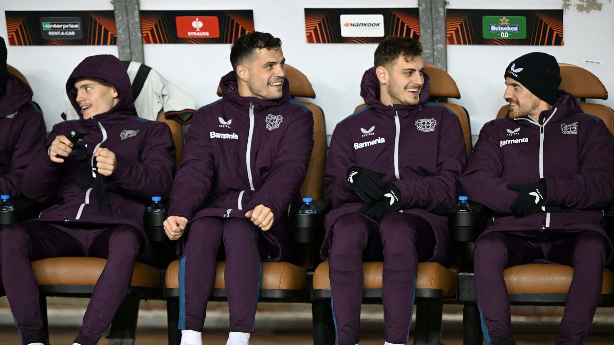 Leverkusens Florian Wirtz (l-r), Josip Stanisic, Granit Xhaka und Jonas Hofmann sitzen auf der Bank.