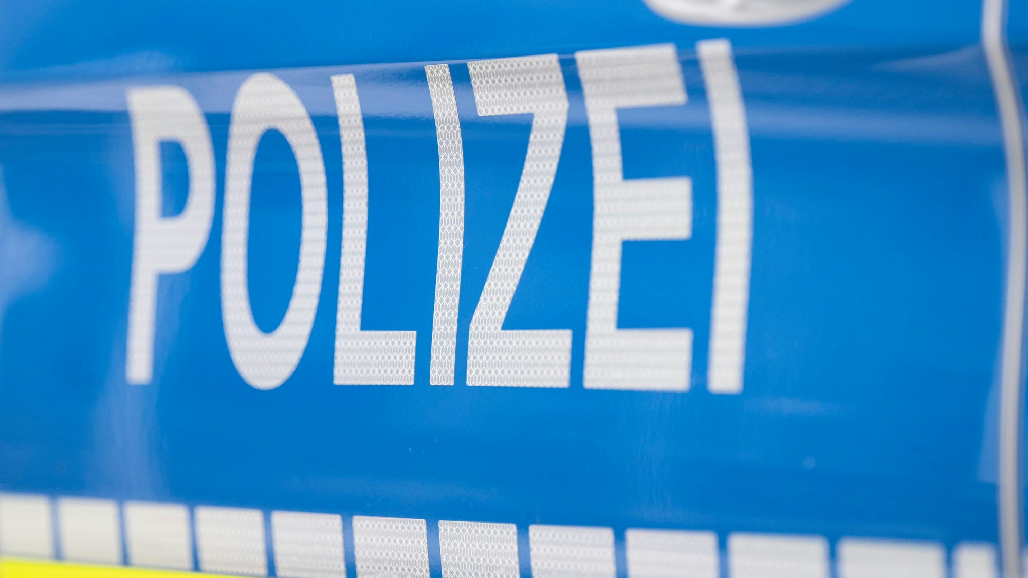 Der Schriftzug Polizei ist auf einem Streifenwagen zu lesen.