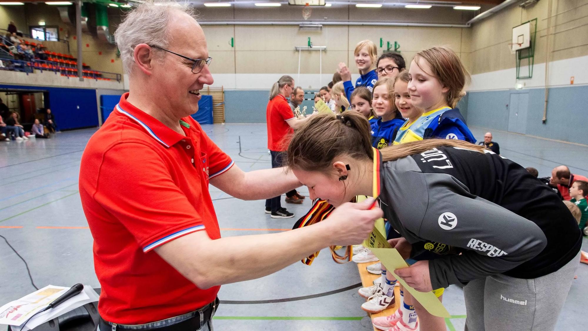 Ein Mann hängt einem Mädchen eine Medaille um.