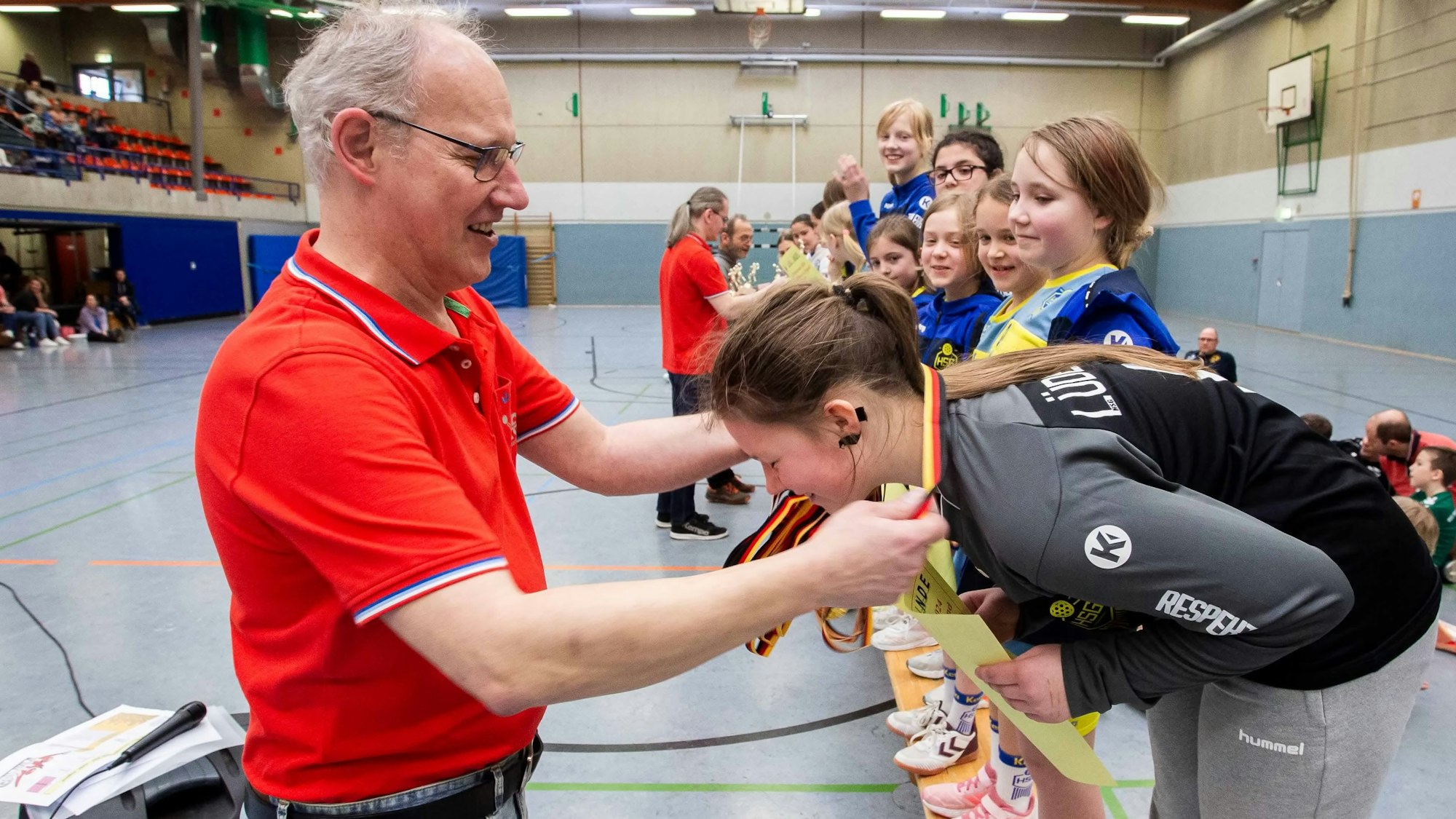 Ein Mann hängt einem Mädchen eine Medaille um.