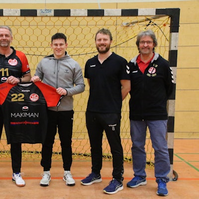 Trainer Peter Trimborn und Marius Schmitz halten das Trikot mit der Nr. 22 hoch. Daneben stehen die beiden Vorsitzenden und René Lönenbach.